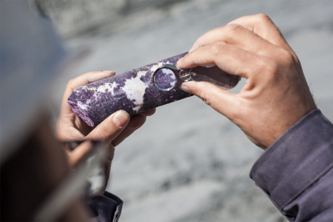 Engineer examining ore specimens with magnifying glass